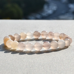 Nahaufnahme eines Naturstein-Armbands mit lichtdurchlässigen Perlen auf Steinoberfläche
