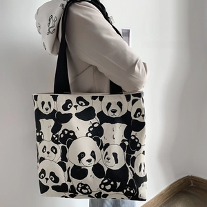 Detail of cute panda print canvas tote bag with thick black straps on model's shoulder
