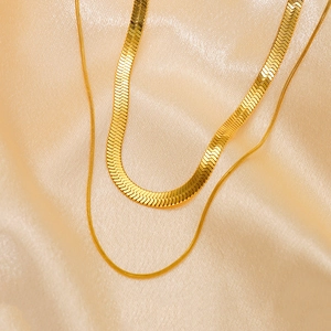 Minimalist gold double layer snake chain necklace on luxurious silk background