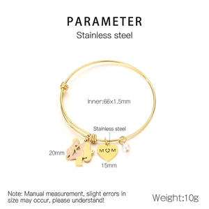 Macro detail of MOM heart charm and pearl on golden stainless steel expandable bracelet