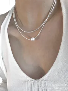 Detail view of double-layer silver choker necklace with synthetic pearl on model's neck