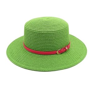 Detail of green straw sun hat featuring a vibrant pink leather band with gold buckle