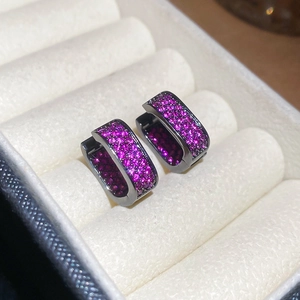 Macro shot of gun-black earrings with pink zircon stones in a velvet box