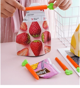 Detailed close-up of carrot-shaped food sealing clips on a pink desk in a kitchen setting