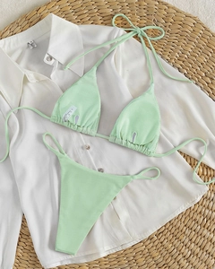 Detail view of mint green ribbed fabric bikini set on a beach vacation background