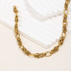 Close-up of 18K gold plated thick woven chain necklace on a white geometric display
