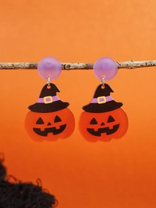 Detail of Halloween pumpkin earrings with wizard hats hanging on a tree branch