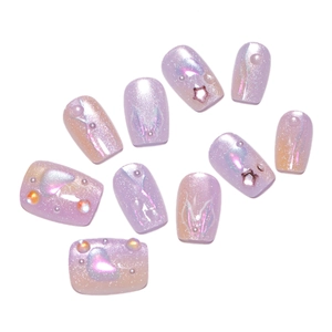 Purple cat eye press-on nails with mermaid pearls and star charms on white background