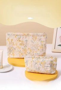 Macro view of floral embroidery on linen cosmetic bag with metal zipper and logo tag