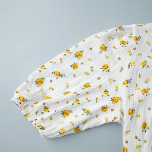 Détail de manches bouffantes en coton blanc avec imprimé floral jaune et élastique