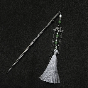 Detailed view of antique silver lotus sword hairpin with green beads and white silk tassels