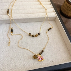 Collier doré avec perles d'œil de tigre et pendentif cheval à bascule en émail rose