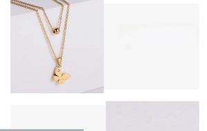 Detail of layered gold necklace set featuring a butterfly pendant and round golden bead