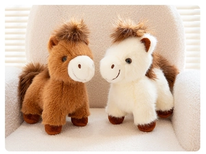 Detailed close-up of two plush pony dolls in brown and white on a soft cream sofa