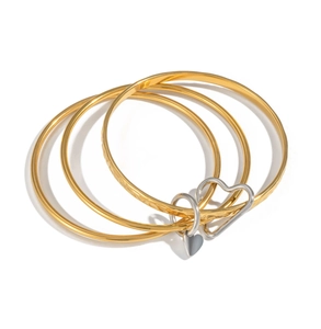 Detail of 4-piece 18K gold stainless steel bangles with silver heart charms on white background