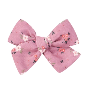 Detail of pink floral fabric bow hair clip with white and orange flower patterns