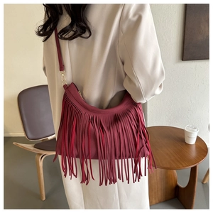 Detail of wine red hobo bag with long fringes and gold hardware on shoulder
