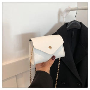 Detailed close-up of white crocodile pattern texture and gold chain on the small square bag