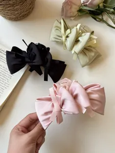 Detailed close-up of bow-knot hair claw clips in black, light blue, and pink satin fabric