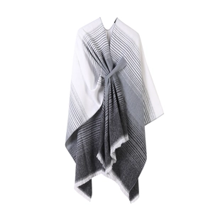 Grey and white striped knitted poncho shawl with fringe tassels on a plain white background