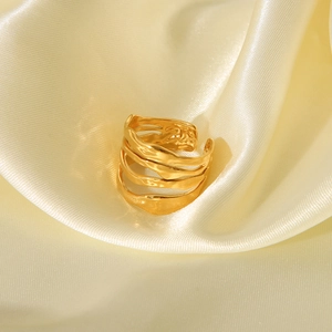 Macro shot of irregular golden wave ring on champagne silk fabric with metallic texture