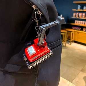 Mini alloy excavator keychain in red and grey colors hanging on a black canvas backpack