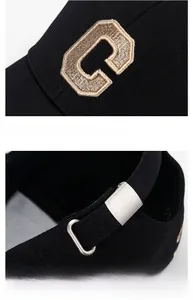 Macro details of golden C embroidery and adjustable metal buckle on a black baseball cap
