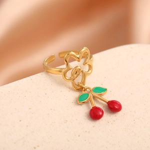 Close-up of golden cherry pendant ring with red and green enamel on a display stand