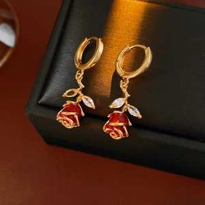 Détail de boucles d'oreilles rose rouge émaillée avec dorure et feuilles de zircon blanc