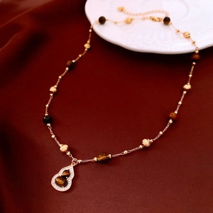 Macro view of gold plated tiger eye bead necklace with a zircon gourd pendant detail