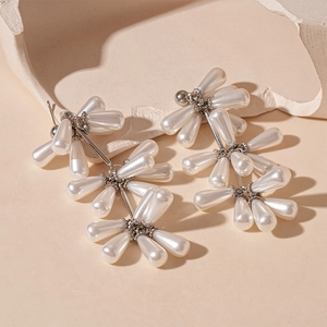 Dettaglio degli orecchini a goccia in argento con perle finte a nappa su pietra beige