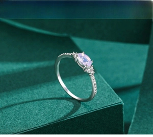Macro view of S925 silver ring with purple oval zircon on dark green velvet background