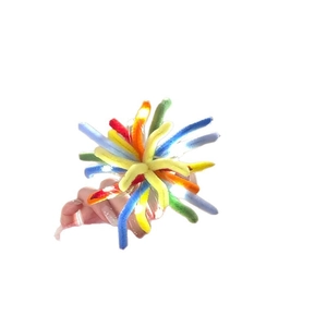 Hand holding a colorful plush pipe cleaner firework hair clip on a clean white background