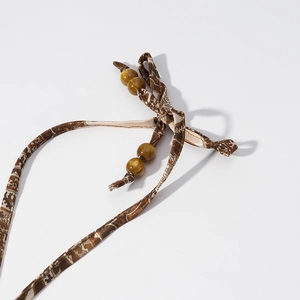 Dettaglio macro del cinturino etnico con perle ambrate su abito estivo boho