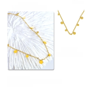 Detail shot of a minimalist gold necklace with round disc charms on a textured background