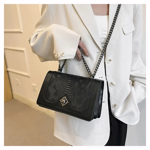Detail of black faux snakeskin leather bag with silver chain strap and diamond clasp