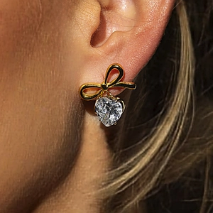 Elegante goldene Schleifenohrringe mit herzförmigem Zirkonia-Anhänger an Model