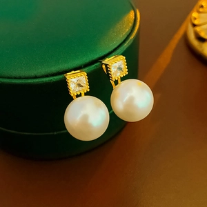 Detailed close-up of gold-plated earrings with square crystal and premium white pearls