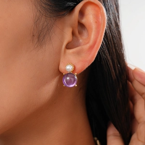 Close-up of vintage golden drop earrings with white pearl and purple gemstone on model