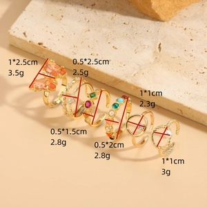 Set of 6 gold butterfly rings with zircon, pearls, and star accents on stone background