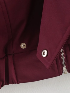 Détail de la veste bordeaux montrant la fermeture éclair métallique et le bouton pression
