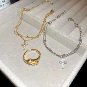Detail of zircon cross pendant necklaces and star ring on a velvet display tray