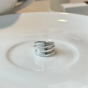 Minimalist 925 sterling silver multilayer intertwined ring shown on white ceramic plate