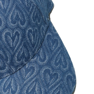 Detailed close-up of dark blue denim baseball cap with woven heart jacquard patterns
