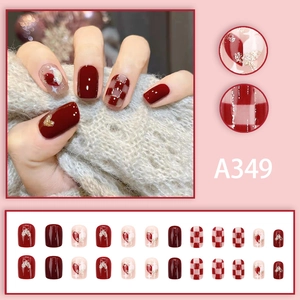 Detail view of red heart pattern and plaid press-on nails with golden glitter accents