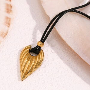 Close-up of golden heart pendant on black cord with seashell and water droplets