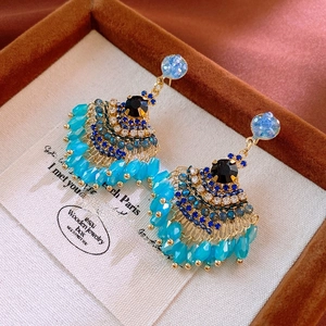 Detail of bohemian fan-shaped earrings with turquoise beads and crystal tassels