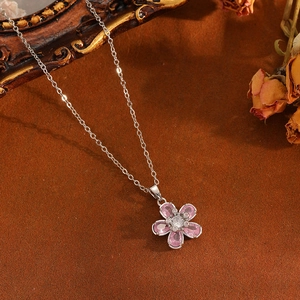 Détail du collier pendentif fleur argentée avec cristaux roses sur fond vintage marron