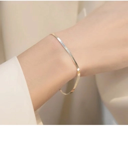 Detailed view of a sleek gold snake bone chain bracelet worn on a female wrist