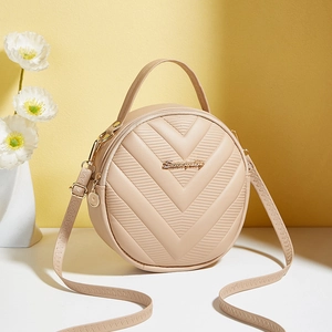 Beige round crossbody bag with V-quilted pattern and metallic logo on white surface